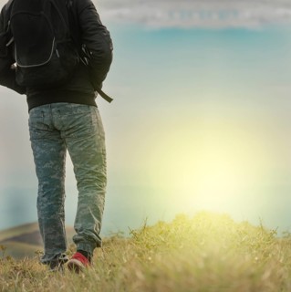 Low angle of backpacker man walking in the countryside. Rear view of backpacker man walking in the
