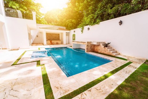 Homemade swimming pool surrounded by trees. Beautiful crystal clear swimming pool in a backyard.
