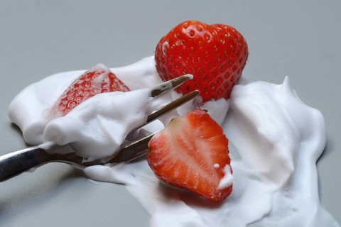 Strawberries on a fork with whipped cream