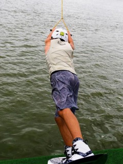 Young man with wakeboard at the jump start, water sports in the wakepark