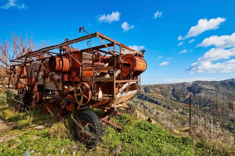 Rusty old combine harvester in front of a picturesque mountain landscape and blue sky, wrecked