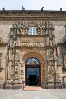 Entrance of a baroque building with richly decorated stone carvings and sculptures above the door,