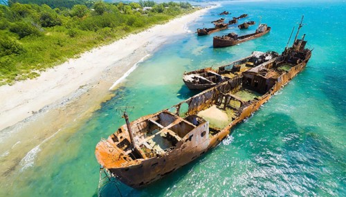 Heavily rusted shipwrecks lie off a coastline in the clear blue sea, symbol photo, AI generated, AI