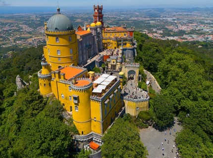 Historic castle in yellow on a hill with an impressive view and surrounded by forest, aerial view,