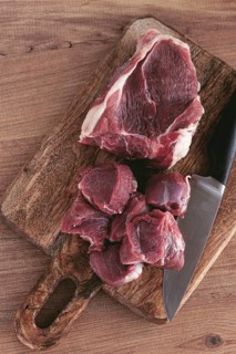 Raw beef meat, sliced on a cutting board, with a knife, no spices, no herbs, top view, wooden