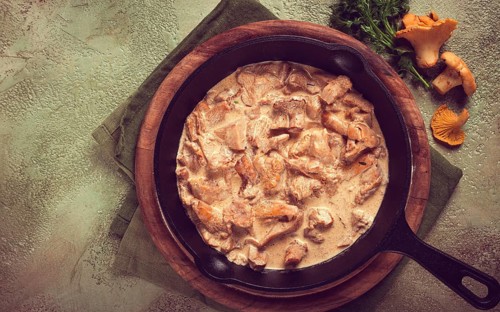 Fried chanterelle mushrooms, in cream sauce, in a cast-iron pan, homemade, no people