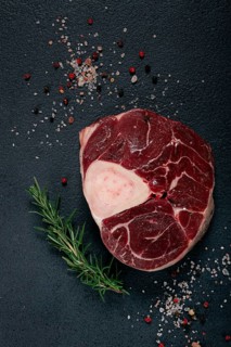 A shank on the bone, raw meat for ossobuco, on the table, with a branch of rosemary, top view, no