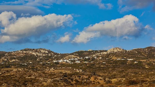View of a hilly landscape with grassy hills under a blue sky with white clouds, West Coast,