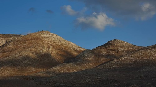 Rocky hills under a blue sky with scattered clouds and shadows, Kassos Island, neighbouring island