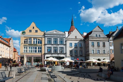 Historic market square with cafés and pigeons, surrounded by impressive architecture, Market