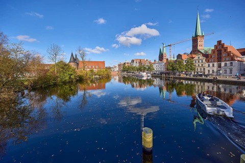 River Trave with quay wall, historic houses, Lübeck Holstentor, church towers of St. Marien and St.