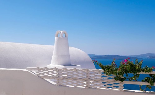 White building with traditional architecture in front of the blue sea and sky, surrounded by