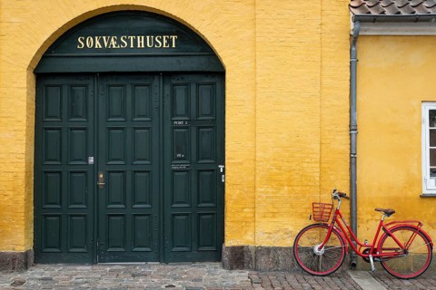 Red bicycle in front of yellow wall, entrance to heritage-protected building Søkvæsthuset, former