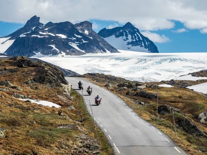 Group of motorcyclists on mountain crossing Sognefjellsvegen, view towards glacier, mountain pass