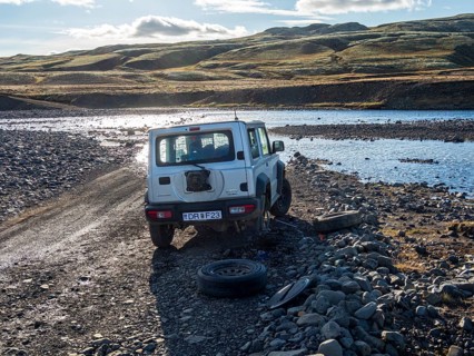 4x4 car with flat tire, change of tire at river crossing on mountain road F206, road to Laki crater