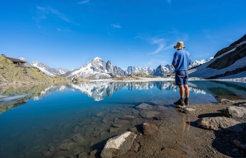 Mountaineer in front of mountain landscape with mountain lake, tourist at Lac Blanc with water