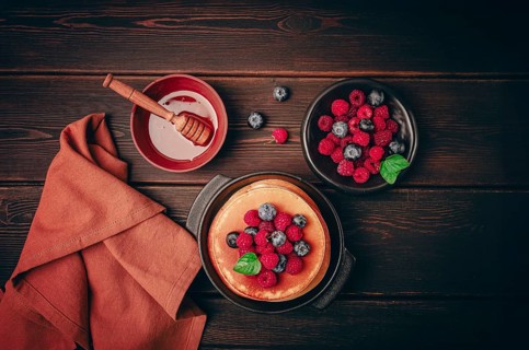 Breakfast, pancakes with berries and honey, top view, homemade, no people, on a wooden background