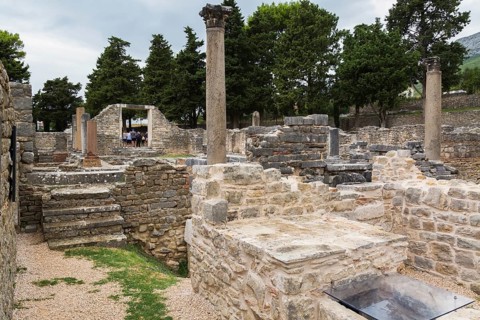Old stone structures and columns plus tourists at ancient 3rd century Roman ruins of Salona near