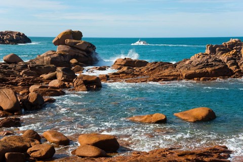 Boat navigating between majestic rocks on a calm coast, Ploumanac'h, Ploumanach, Perros-Guirec,