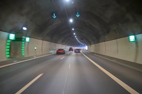 Cars drive through an illuminated concrete tunnel under shining lights, Switzerland, Europe