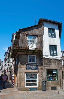 Rustic old stone house with balconies and a shop in an urban environment, house in Rúa do Vilar,