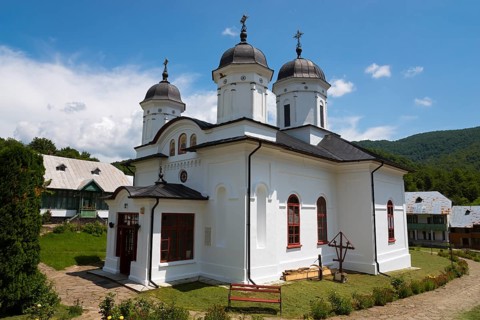 White church with several domes and crosses under a sunny sky, Orthodox nunnery Suzana, Maneciu,