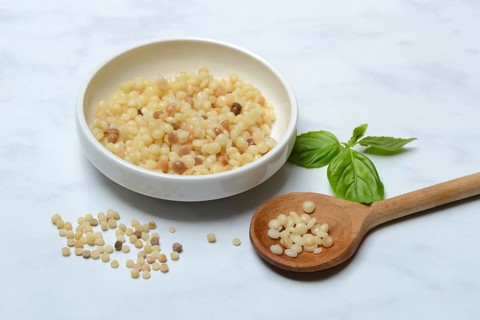Cooked fregola in bowl with wooden spoon, pasta variety from Sardinia, Italy, Europe