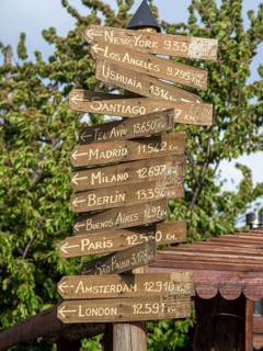 Signpost showing directions to major world cities, Plaza del Arma, Futaleufu, Chile, South America