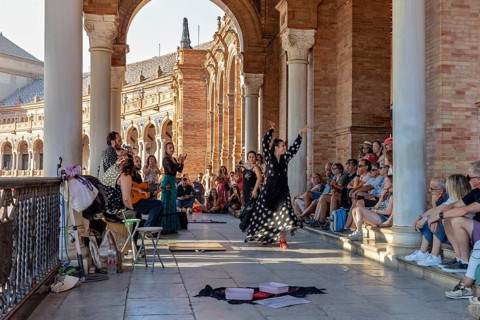 Flamenco dancers and guitarists perform in front of a tense audience under masonry arches, Seville