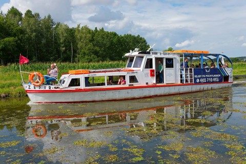 A white and red passenger boat sails along a quiet canal, surrounded by green nature, Zefir ship,