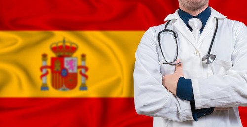Male doctor with stethoscope on Spain flag. Doctor holding stethoscope on Spanish flag