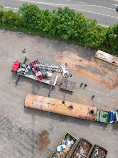 Detailed view of a construction site with a crane and several workers as well as various vehicles,