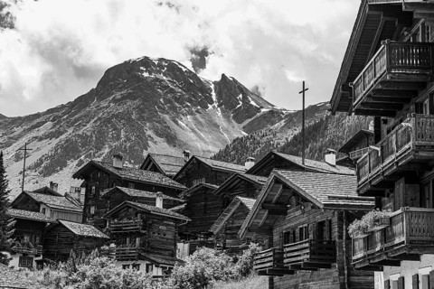 Nested old wooden houses, in the background the summit of the mountain Scex de Marenda, historic