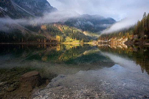 The Vordere Gosausee in autumn with a view of the Gasthof Gosausee. Sun and clouds. Overcast.