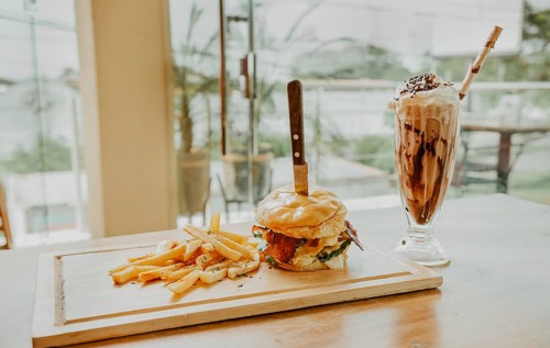 Hamburger with fries and milkshake served on wooden board with space for text