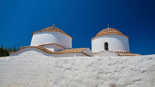 Two white-painted church towers with round, red-tiled roofs against a bright blue sky, Chora, Old
