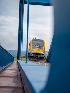 Train approaching from behind blue subway on rails, track construction, rail delivery for Hermann