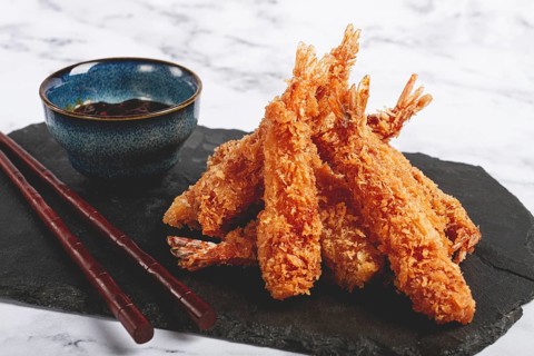 Shrimp in tempura, deep fried, on black slate, with sauce, light marble table, no people