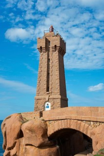 Lighthouse above an arch of rocks in front of a blue sky with clouds, Phare de Men Ruz,