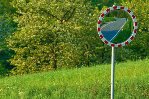 Traffic mirror reflecting a road, trees and meadow in the background, Odenwald, Hesse, Germany,