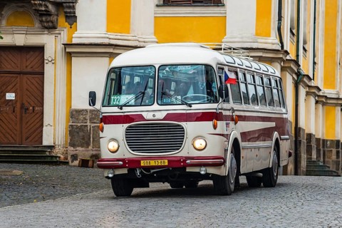 A traditional bus in front of a magnificent yellow historical building in an urban environment,