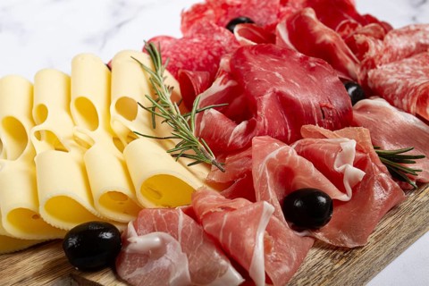 Assorted meat, appetizer, prosciutto, salami and ham, with maasdam cheese and olives, on a wooden