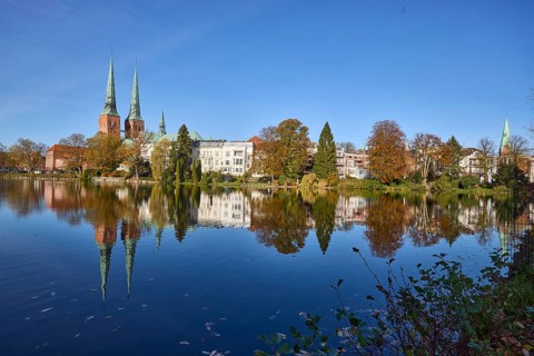 Mill pond with general buildings, Lübeck Cathedral and trees, symmetrical reflections on the water