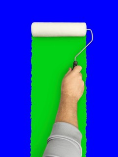 Male hand rolling paint roller over blue and green screen background