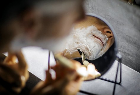 Symbolic photo on the subject of shaving. A man shaves his beard with a wet razor. Berlin, 13.08