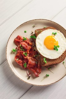 Breakfast, fried egg with bacon, micro-green, on a light background, no people, selective focus