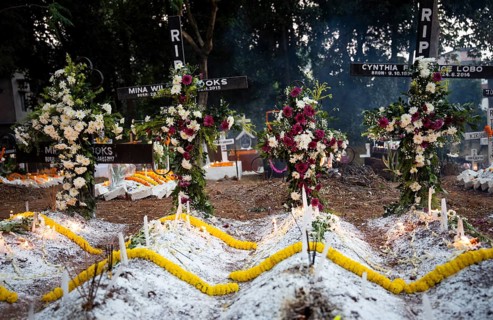 People from Christian community light candles and offer prayers on the grave of their relative