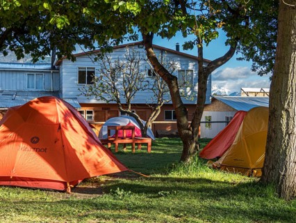 Campground of hostel Bellavista, orange and yellow tents below trees, Puerto Rio Tranquilo,