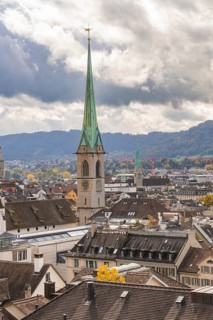 Close-up of a church tower with city and hills in a cloudy sky, Zurich, Switzerland, Europe
