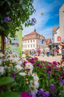 Street scene with a green flower arrangement in the foreground and people in an urban environment